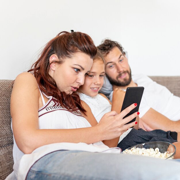 Plano medio de la familia mirando juntos el teléfono