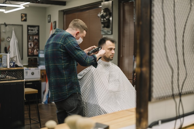 Plano medio del hombre cortándose el pelo