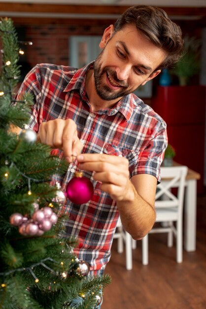 Plano medio hombre feliz decorando el árbol de navidad