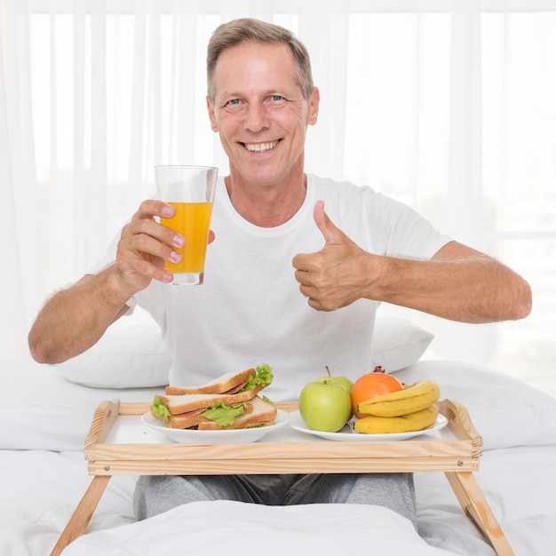 Plano medio hombre feliz con jugo mostrando aprobación