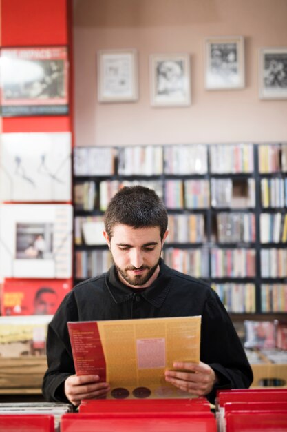 Plano medio de un hombre joven en busca de vinilos en la tienda.