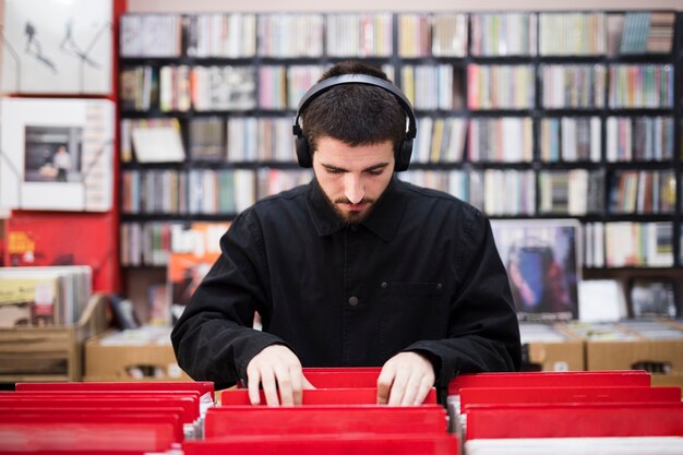 Plano medio de un hombre joven en busca de vinilos en la tienda.