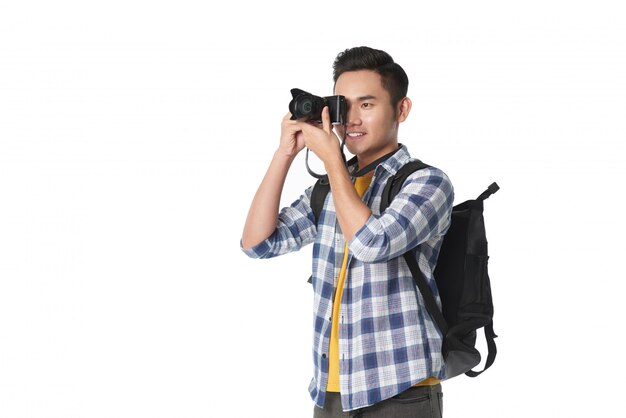 Plano medio del hombre con mochila tomando una foto con su cámara profesional
