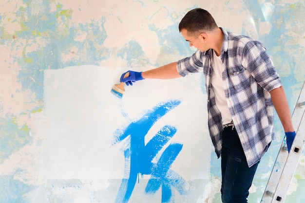 Plano medio del hombre paiting una pared