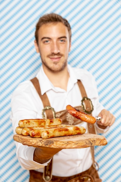 Plano medio del hombre que sostiene el plato de salchichas alemanas