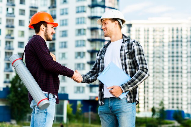 Plano medio del ingeniero y arquitecto dándose la mano.