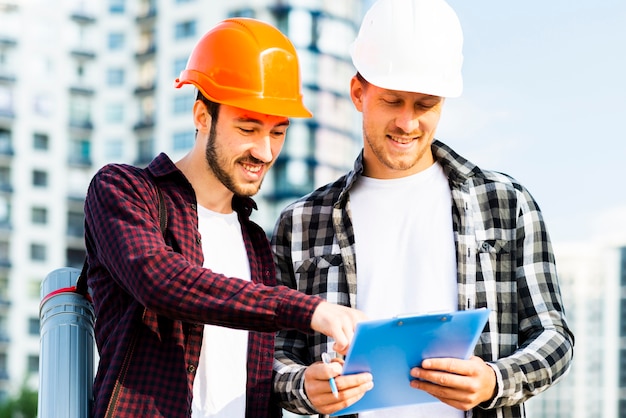 Foto gratuita plano medio de ingeniero y arquitecto mirando portapapeles