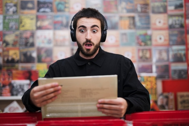 Plano medio de un joven escuchando música en una tienda de vinilos.