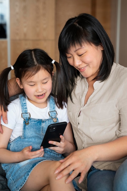 Plano medio madre y niña con teléfono