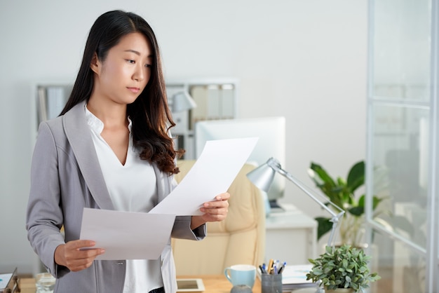 Plano medio de mujer asiática comprobando documentos comerciales