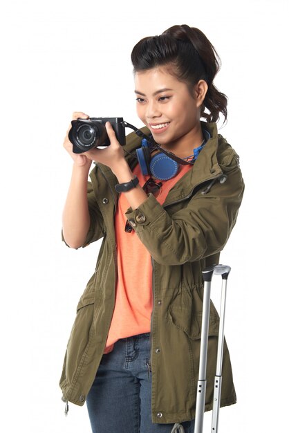 Plano medio de mujer asiática sosteniendo una cámara fotográfica tomando foto