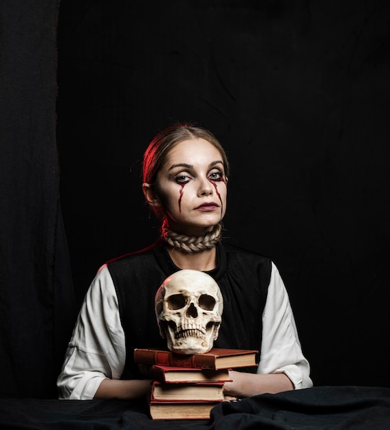 Plano medio de mujer con libros y calavera