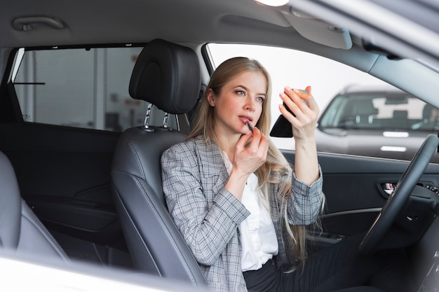 Plano medio de mujer poniéndose lápiz labial