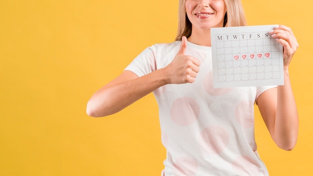 Plano medio de la mujer que muestra su calendario de época y golpea