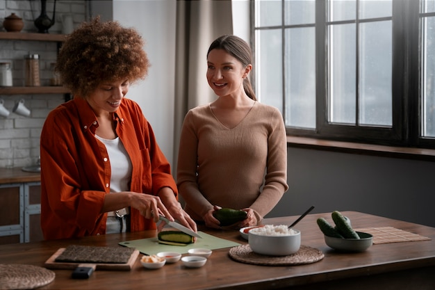 Plano medio mujeres aprendiendo a hacer sushi.