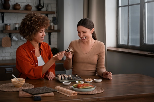 Plano medio mujeres aprendiendo a hacer sushi.