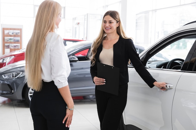 Plano medio de mujeres en concesionario de automóviles