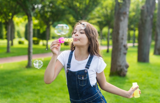 Plano medio niña linda haciendo pompas de jabón