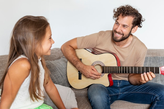 Foto gratuita plano medio del padre tocando la guitarra