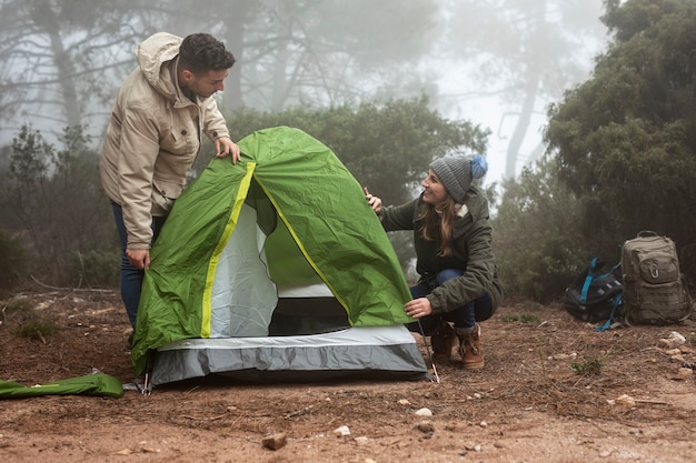 Plano medio pareja colocando carpa verde