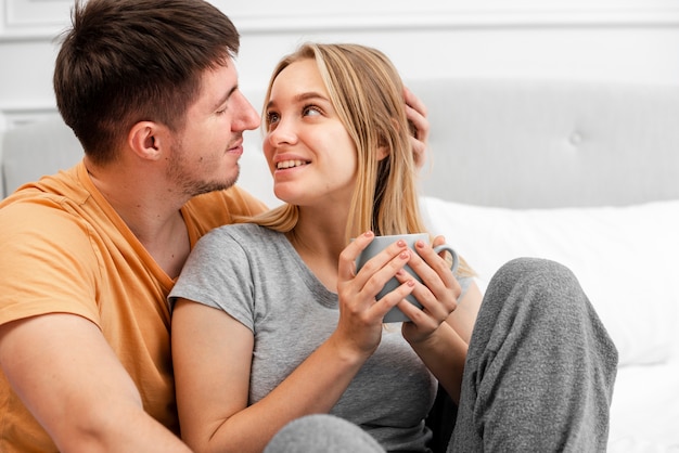 Plano medio pareja feliz con café en la cama