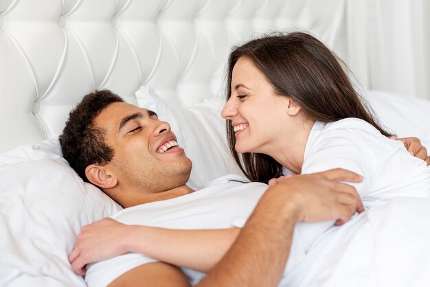 Plano medio pareja feliz en la cama juntos