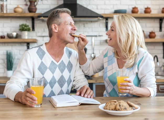 Plano medio pareja feliz desayunando juntos