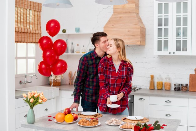 Plano medio pareja feliz de pie en la cocina