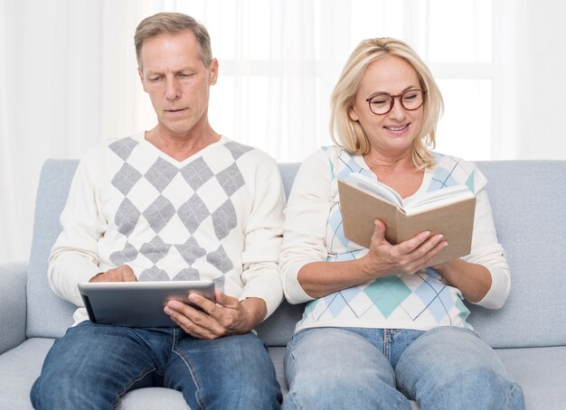 Plano medio pareja feliz en el sofá leyendo