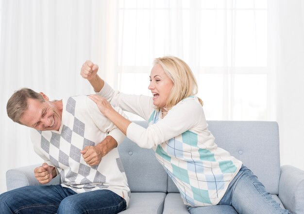 Plano medio pareja jugando en el sofá