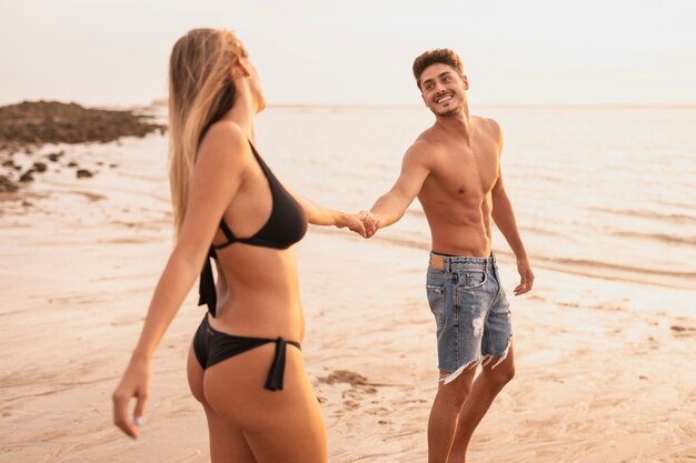 Plano medio de pareja sonriendo y tomados de la mano