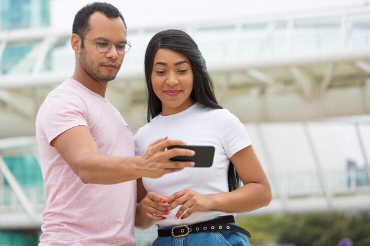Foto gratuito plano medio de sonrientes amigos mirando el teléfono inteligente