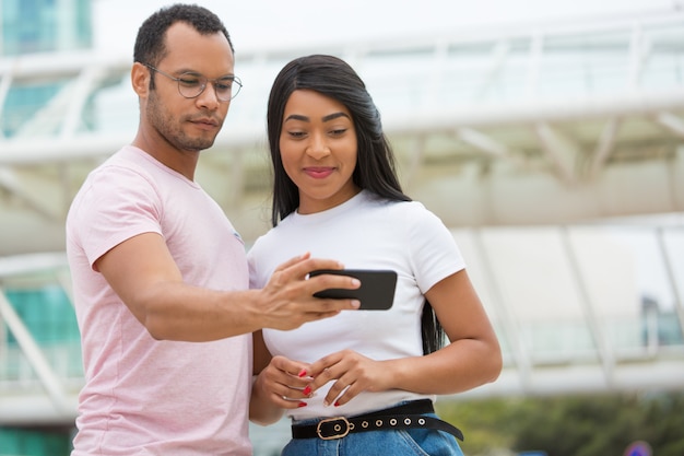 Plano medio de sonrientes amigos mirando el teléfono inteligente