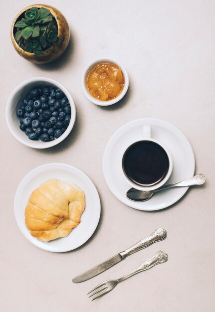 Foto gratuita planta de cactus; mermelada; arándano; taza de café y pan sobre fondo blanco.