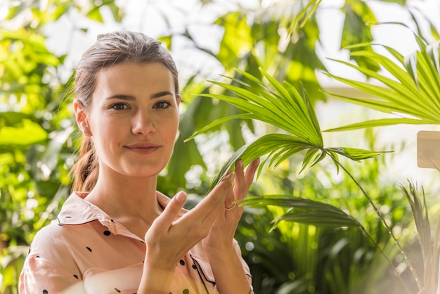 Planta conmovedora de la mujer joven en casa verde