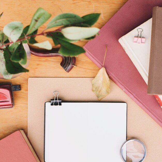 Planta ramita sobre mesa con cuadernos