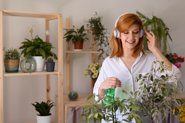 Planta de riego de mujer sonriente de tiro medio