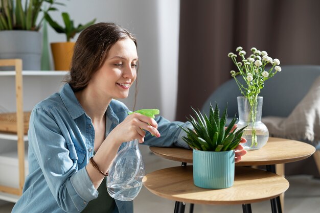 Planta de riego de mujer sonriente de tiro medio