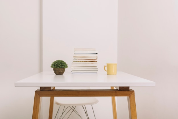 Planta y taza cerca de libros sobre la mesa