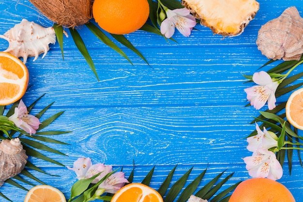 Plantar hojas y frutos cerca de flores con conchas marinas.