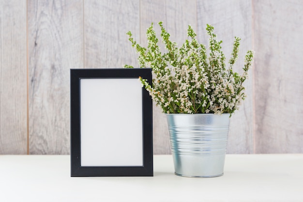 Foto gratuita plantas decoradas en maceta de plata y marco de fotos en blanco en la mesa