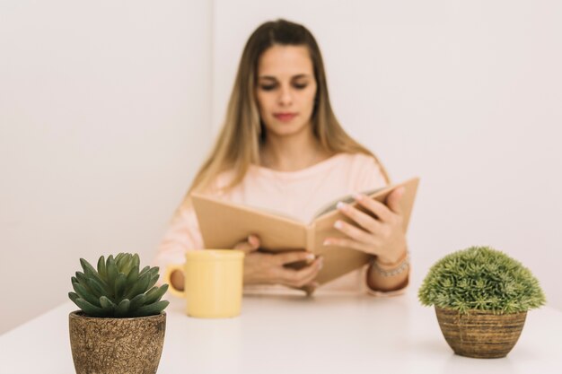 Plantas en macetas cerca de la mujer leyendo