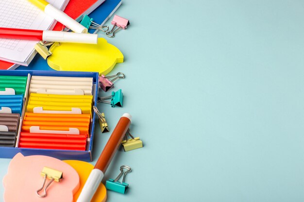 Plastilinas de colores de la mitad de la vista superior con cuadernos en el color de la pared azul escuela niños libro para niños