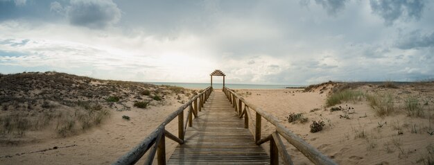 Plataforma larga de madera que conduce a la playa bajo el cielo nublado