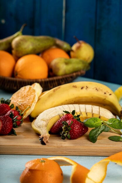 Plátano fresco, naranja y fresas en una tabla de madera