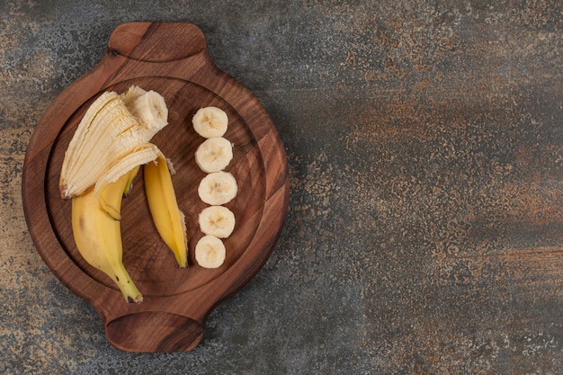 Foto gratuita plátano pelado y en rodajas sobre tabla de madera