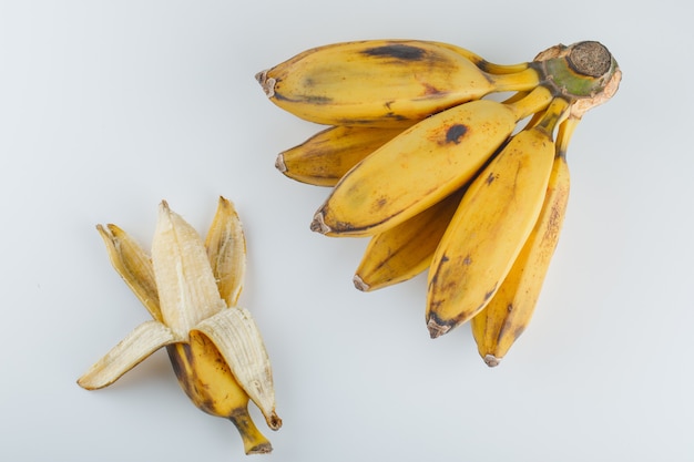 Plátanos maduros amarillos sobre un fondo blanco.