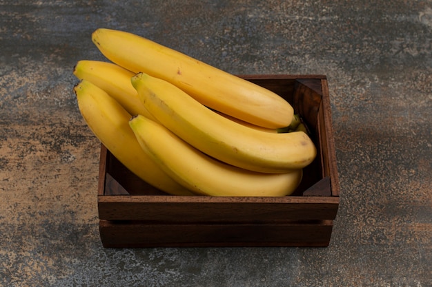 Plátanos maduros en la caja, sobre la superficie de mármol