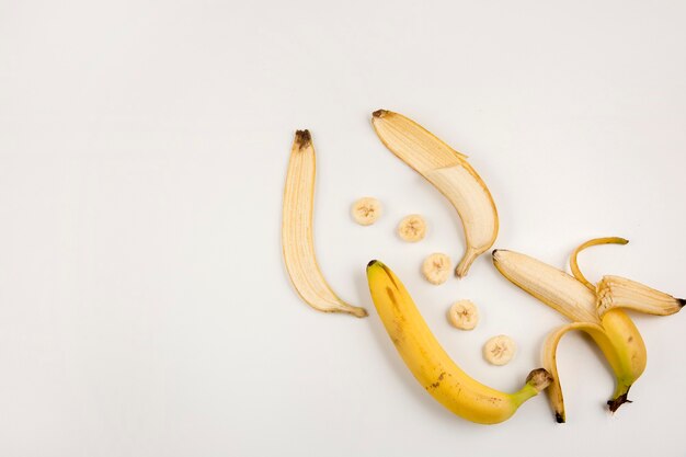 Plátanos pelados y en rodajas sobre fondo blanco en la esquina