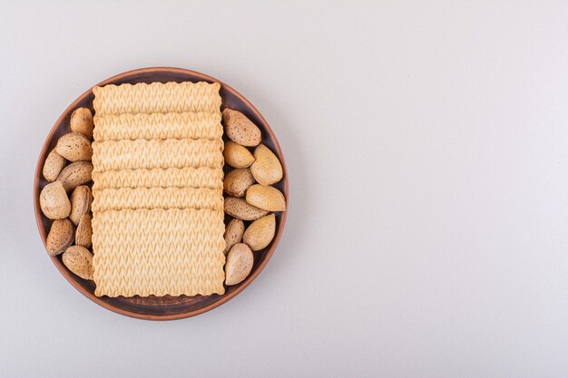 Plato de almendras orgánicas sin cáscara y galletas sobre fondo blanco. Foto de alta calidad